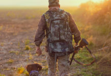 Gestione della caccia, Centinaio: “Il ministero dell’Agricoltura rivuole le competenze” gestione della caccia: cacciatore con cane e fucile da dietro