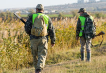 Legge sulla caccia, Cia consegna proposta a Centinaio legge sulla caccia, due cacciatori di spalle con giubbotto alta visibilità e fucile
