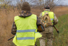 Calendario venatorio delle Marche e durata dei piani faunistico-venatori: l’ordinanza del Tar calendario venatorio delle marche: due cacciatori con gilet alta visibilità, di spalle