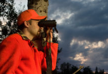 In Toscana dicembre è il mese della sicurezza a caccia sicurezza a caccia: cacciatore in alta visibilità guarda nel binocolo