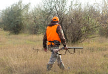 Calendario venatorio del Veneto: la proposta di Arcicaccia Calendario venatorio del Veneto: cacciatore di spalle con gilet arancione alta visibilità, fucile nella mano destra