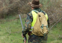 Iscrizione agli Atc toscani: tre associazioni venatorie chiedono riduzione quote Iscrizione agli Atc toscani: cacciatore di spalle con cappello, zaino e gilet alta visibilità, fucile nella mano sinistra