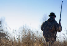 Caccia in Emilia Romagna: Bonaccini riapre Caccia in Emilia Romagna: cacciatore di spalle con zaino sulle spalle, cappello in testa e carabina nella mano destra