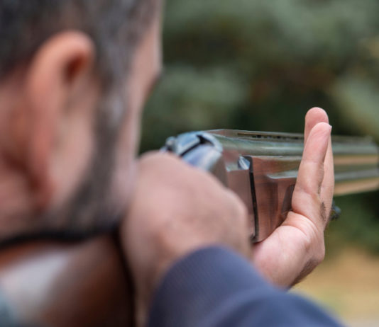 Caccia in Lombardia, da consiglio regionale ok alla riforma Caccia in Lombardia: cacciatore prende la mira per sparare, immagine da dietro
