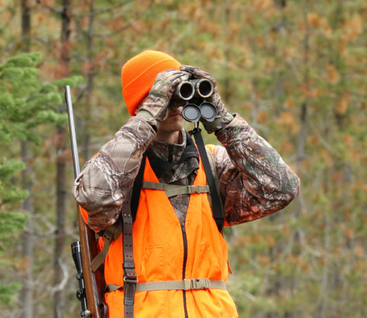Perplessità di Arcicaccia sulla legge di riforma della caccia in Lombardia legge di riforma della caccia in Lombardia: cacciatore con gilet alta visibilità guarda in binocolo