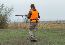 Slitta consegna del tesserino venatorio in Campania Slitta consegna tesserino venatorio in Campania: cacciatore con gilet alta visibilità e fucile in mano