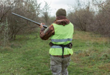 Verso la modifica della legge sulla caccia in Lombardia legge sulla caccia in Lombardia: cacciatore di spalle con fucile tra le mani, abbigliamento alta visibilità
