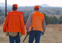 Associazione unica dei cacciatori, la richiesta dell’Arcicaccia Associazione unica dei cacciatori: due cacciatori di spalle indossano gilet arancio alta visibilità