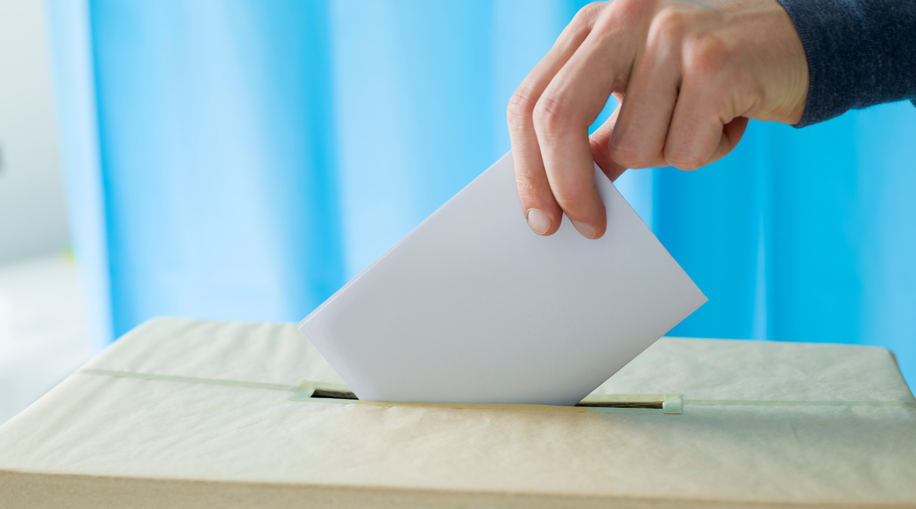 Referendum sulla caccia: mano deposita scheda in urna elettorale