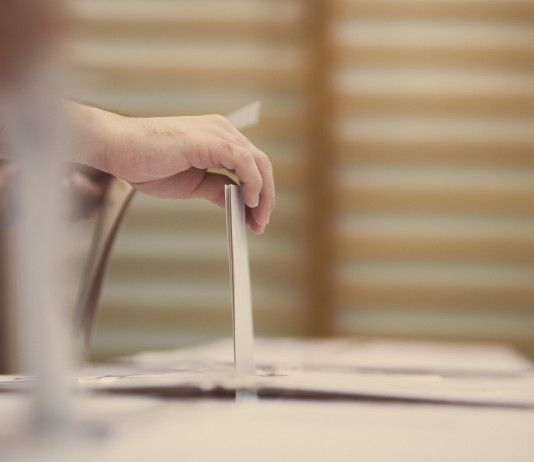 Referendum sulla caccia: la posizione della cabina di regia Referendum sulla caccia: mano deposita urna nella scheda, spalliera di una palestra sullo sfondo