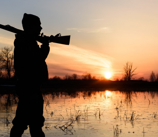 Associazione unica dei cacciatori: nuovo rilancio di Arcicaccia Associazione unica dei cacciatori: cacciatore in ambiente acquatico con fucile in spalla