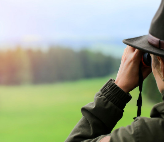 Referendum e legge sulla caccia: il commento della Libera Caccia Referendum e legge sulla caccia: cacciatrice di spalle con binocolo