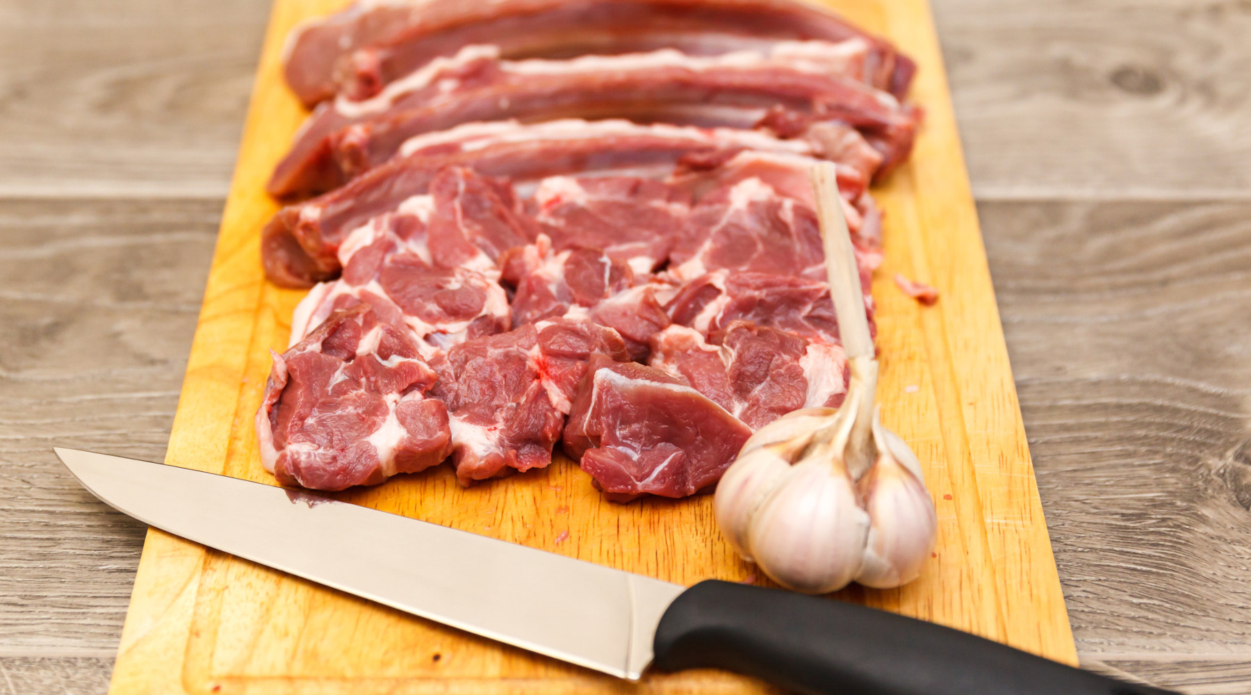 Carne di cinghiale nei punti vendita Metro: carne di cinghiale su tagliere, con aglio e coltello