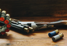 Proroga del porto d’armi e stato d’emergenza: è cambiato qualcosa? Proroga del porto d’armi: fucile da caccia con cartucce su tavolo di legno