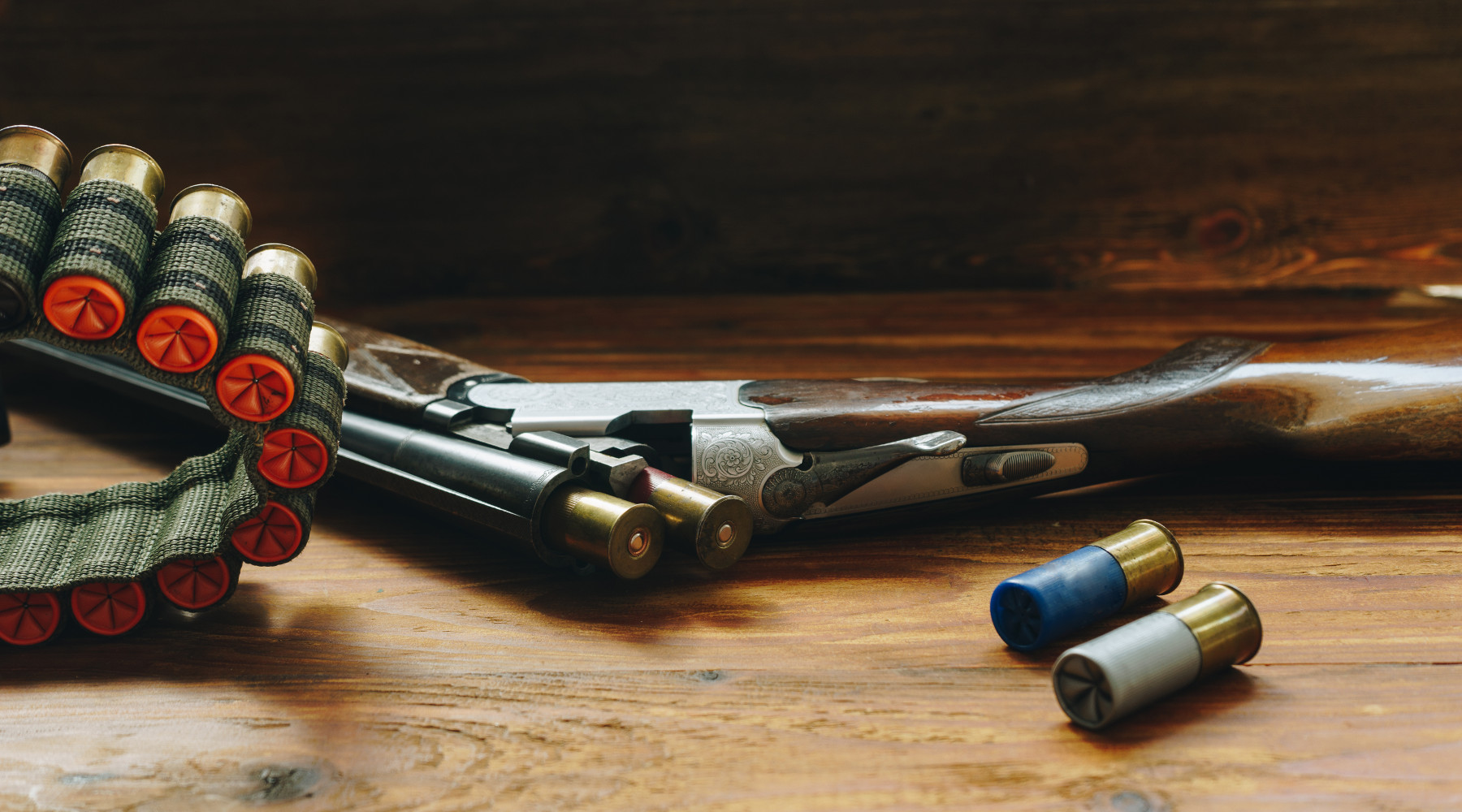 Proroga del porto d’armi: fucile da caccia con cartucce su tavolo di legno