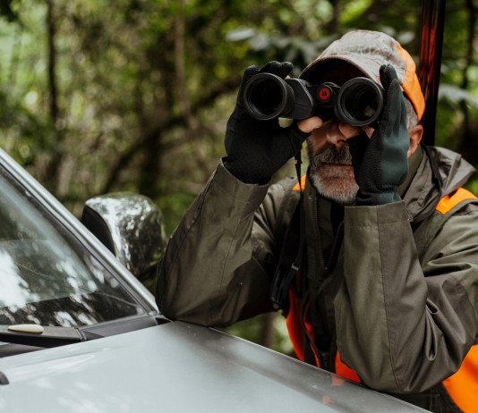 Le informazioni sulla caccia meno conosciute Le informazioni sulla caccia meno conosciute: cacciatore con binocolo e gilet alta visibilità
