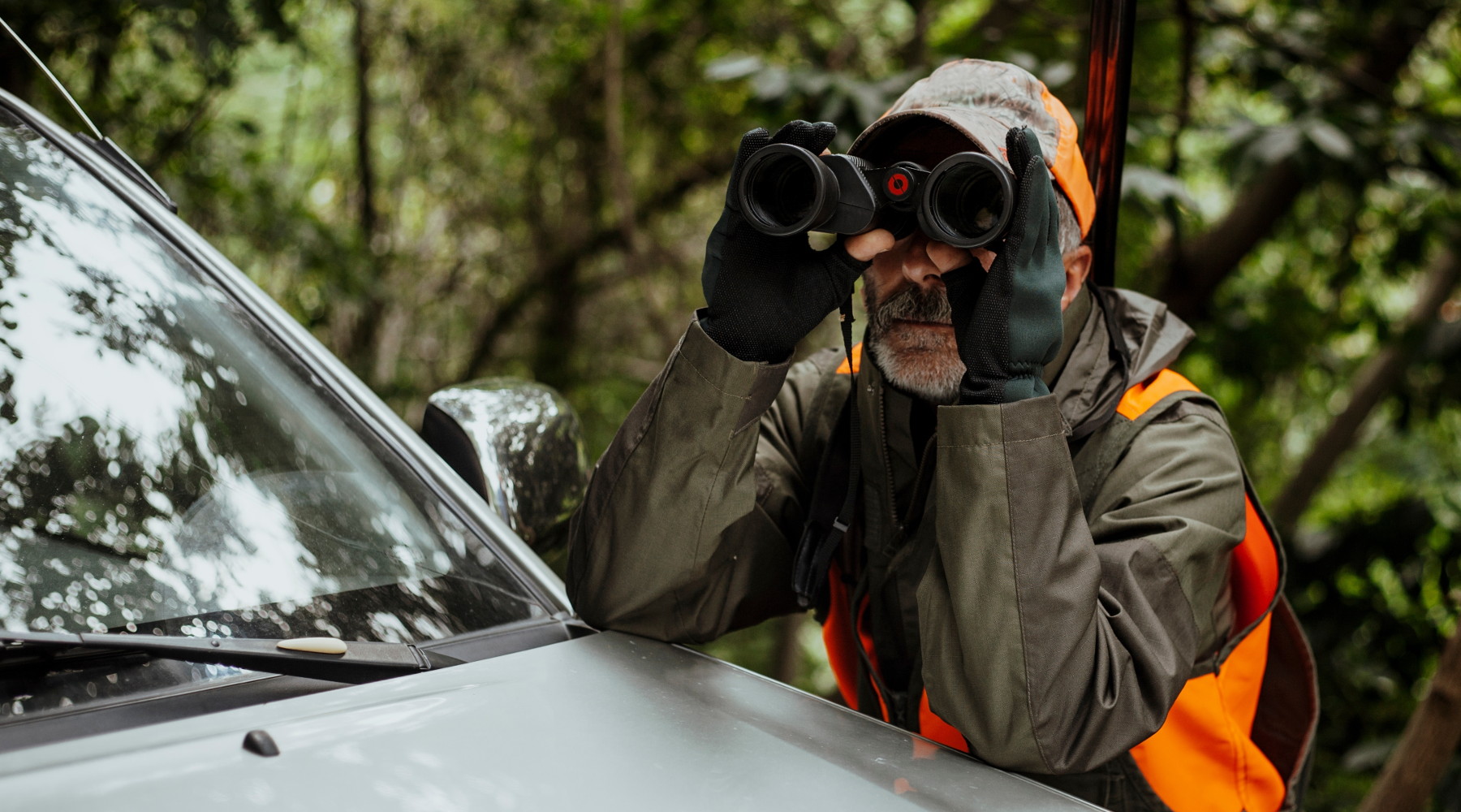 Le informazioni sulla caccia meno conosciute: cacciatore con binocolo e gilet alta visibilità