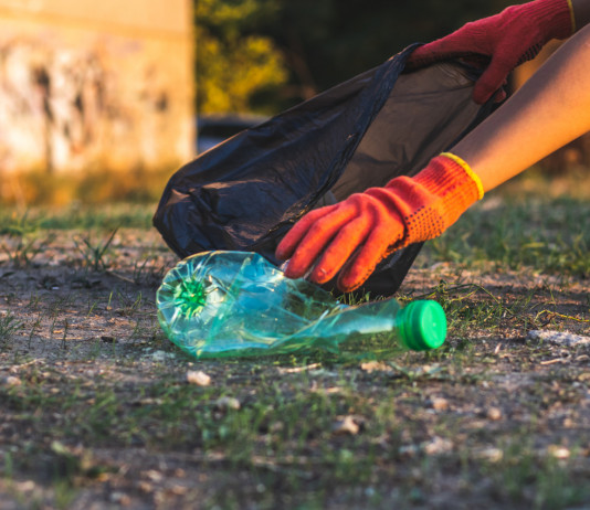 Diffuso il bilancio sociale 2022 della Federcaccia: impatto raddoppiato Diffuso il bilancio sociale 2022 della Federcaccia: mano con guanto raccoglie bottiglia di plastica per pulire la foresta e introdurla nel sacco nero della spazzatura
