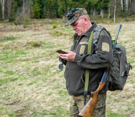 Ribaltata sentenza del Tar sulla rappresentanza dei cacciatori negli Atc Ribaltata sentenza del Tar sulla rappresentanza dei cacciatori negli Atc: cacciatore con fucile in spalla mentre guarda telefono