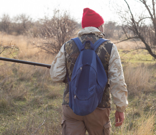 Sulla riforma della legge sulla caccia opposizioni pronte a combattere Sulla riforma della legge sulla caccia opposizioni pronte a combattere - cacciatore di spalle, cappello rosso, fucile in mano